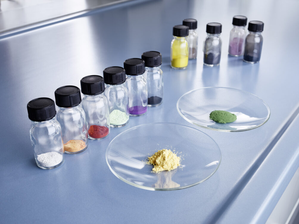 Glass vials in lab with different colored powders and two petri dishes